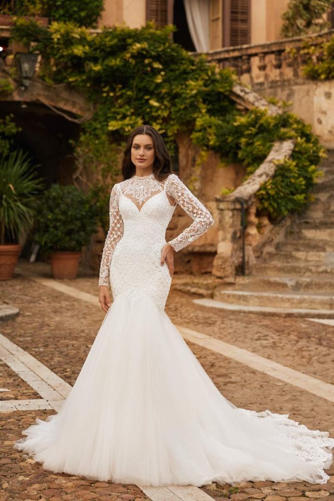In questa foto, una modella posa indossando un abito a semi-sirena in tulle e pizzo di Monica Loretti