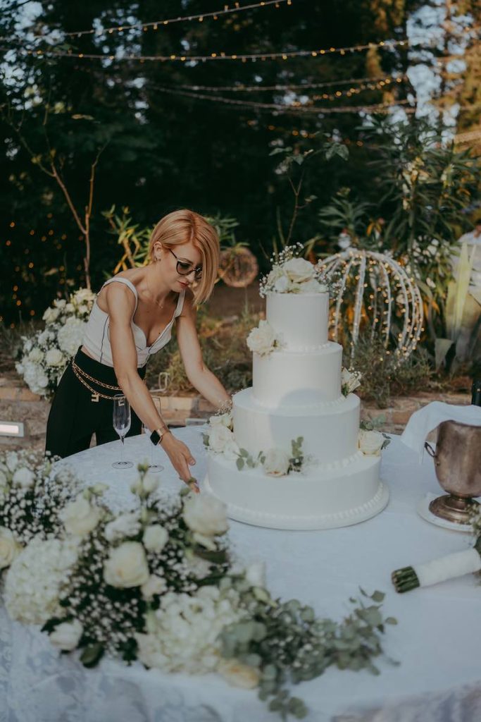 In questa foto, la Wedding Planner Ada Di Donato mentre decora il tavolo di una torta nuziale con di colore bianco e con fiori abbinati