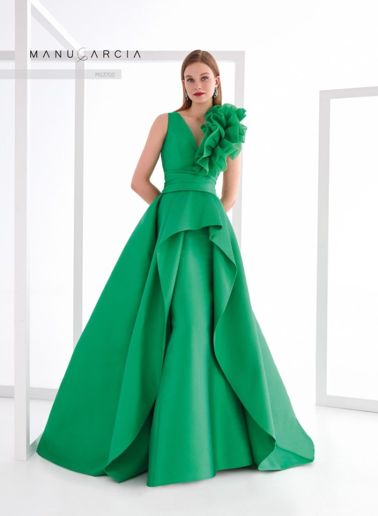 In questa foto, una modella posa indossando uno degli abiti da cerimonia Higar Novias Group 2026 della linea Manu García 2026 color verde smeraldo, con silhouette ad A, maxi drappeggio frontale, scollo a V, maxi rouches sulla spalla sinistra 