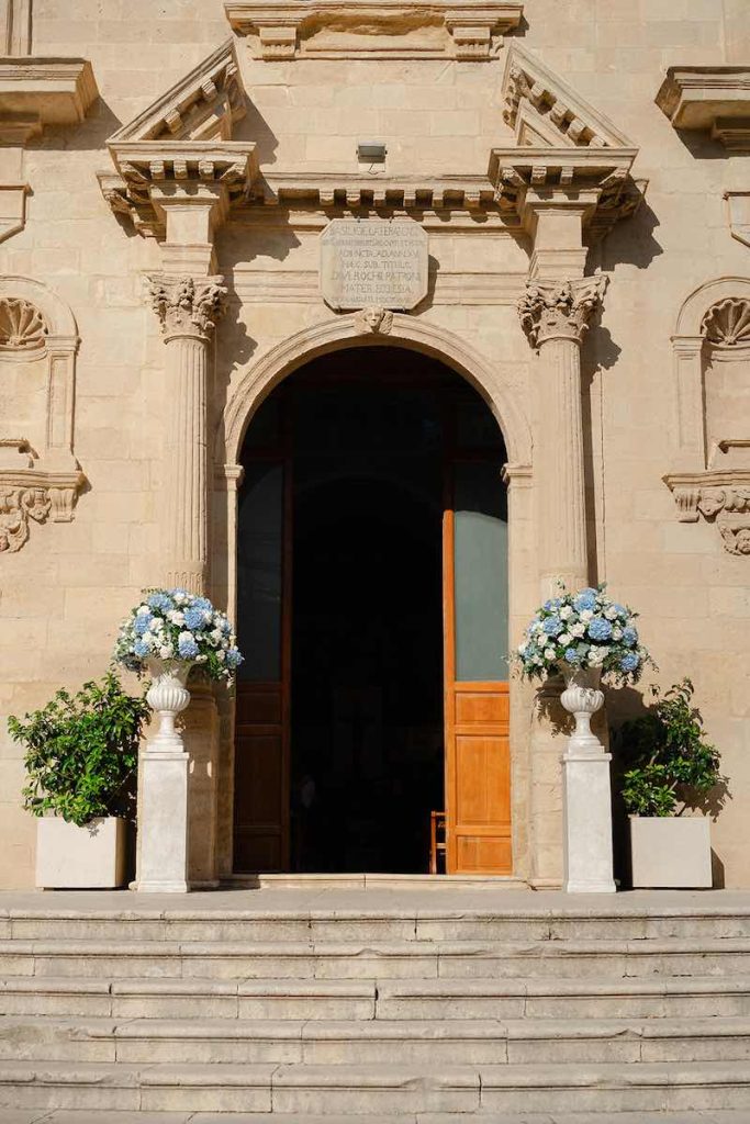 In questa foto, l'ingresso della Chiesa di San Rocco di Scordia allestita da Panta Rhei con vasi di ortensie di colore azzurro e rose di colore bianco