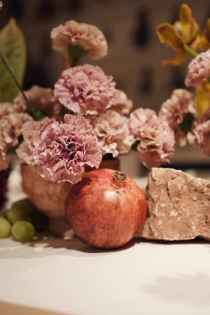 In questa foto il dettaglio di una decorazione per matrimonio con fiori di colore rosa e melagrane