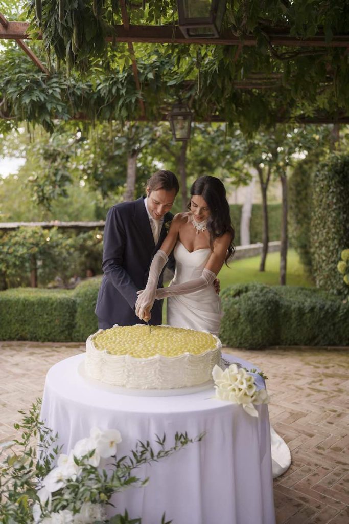 In questa foto due sposi al taglio di una torta nuziale ad un piano decorata con frutta di colore verde