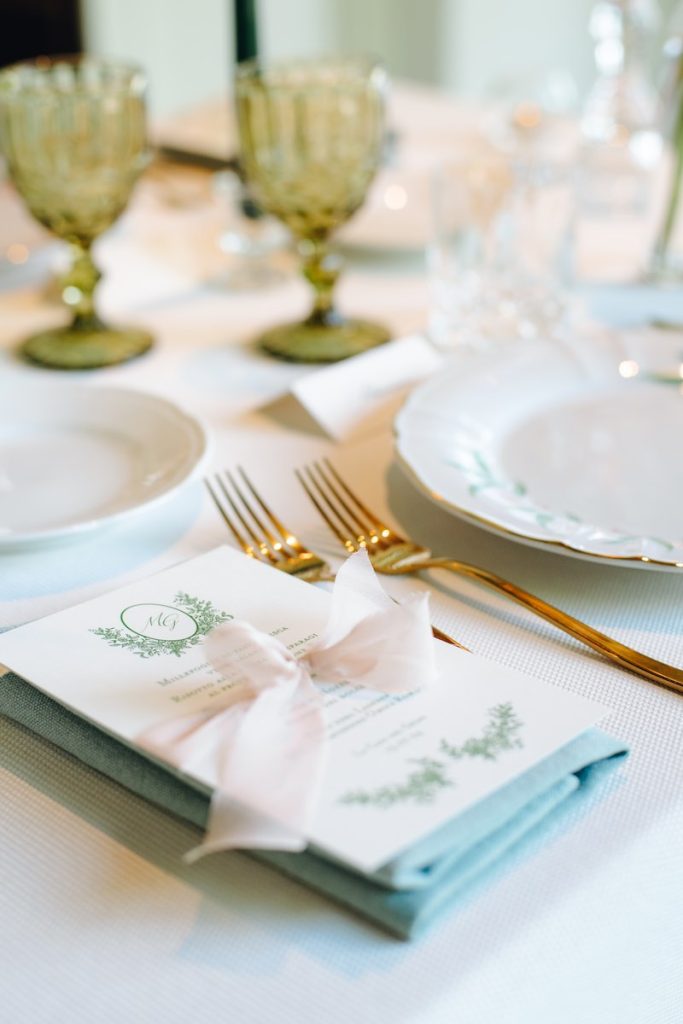 In questa foto il dettaglio di una mise en place per matrimonio nei toni del rosa, dell'azzurro e dell'oro con menù personalizzato