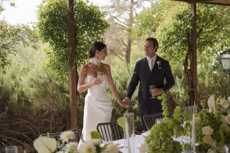 In questa foto due sposi sorridenti che camminano dietro ad un tavolo imperiale decorato per il loro matrimonio da Filomena D'Amelio