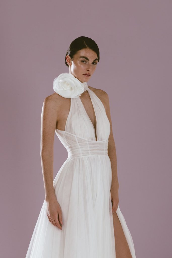 In questa foto una modella indossa un abito in tulle della linea Futura by Luisa Lotti modello scivolato con spacco frontale, con scollo all'americana e scollo a V e fiore 3D al collo