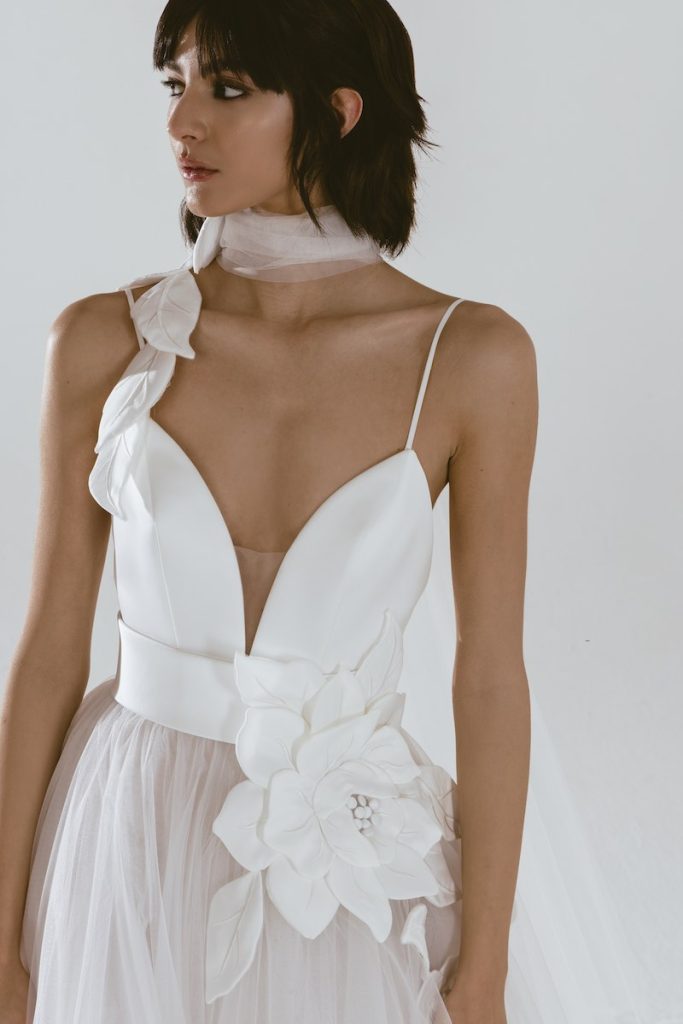 In questa foto una modella posa indossando un abito scivolato con gonna in tulle, corpetto in satin con scollo a V e inserti floreali 3D sul corpetto e sul punto vita
