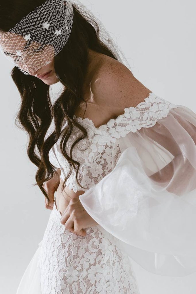 In questa foto una modella posa indossando un abito due pezzi con gonna e corpetto in pizzo floreale con maniche balloon in organza di seta