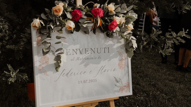 In questa foto, il Welcome Table del matrimonio di Flavia e Federico allestito in un quadro decorato con fiori da Manuela Marrale