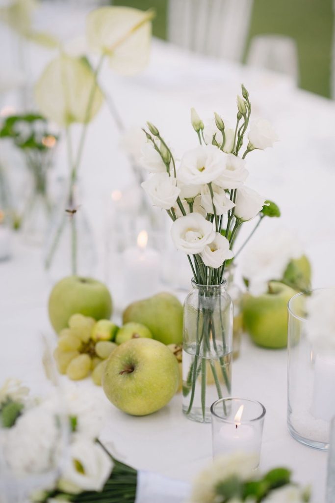 In questa foto il dettaglio di una mise en place nei toni del bianco e del verde con fiori e mele realizzata da Silvia Baldan
