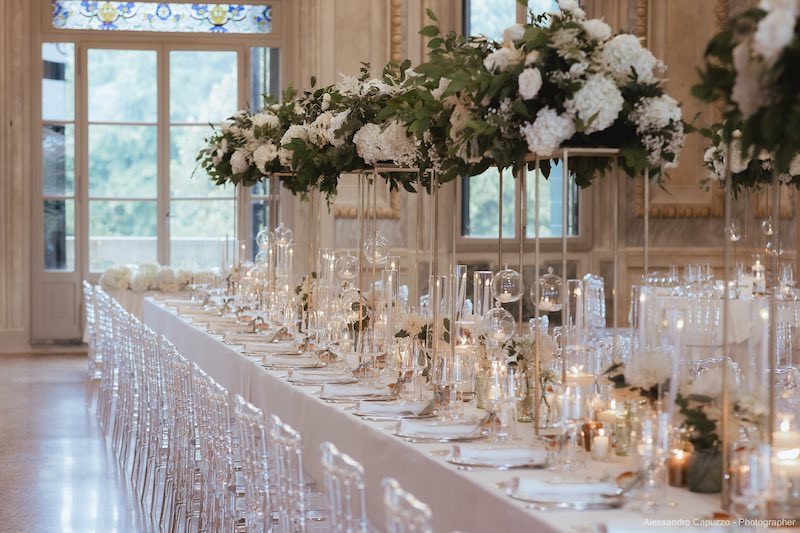 In questa foto un tavolo imperiale decorato da Silvia Baldan con alzate di fiori di colore bianco e candele 