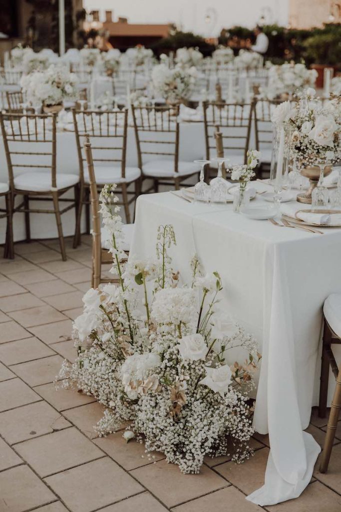 In questa foto il dettaglio di una composizione floreale nei toni del bianco davanti ad un tavolo imperiale per matrimonio allestito da Simona Filasto