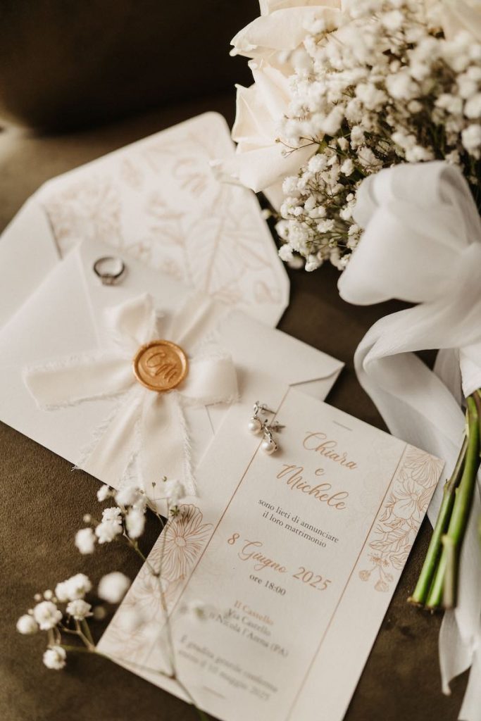 In questa foto partecipazioni di nozze nei toni del bianco e dell'oro