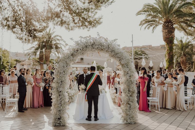 In questa foto il matrimonio civile di una coppia, allestito in una piazza con un arco di gypsophila bianca