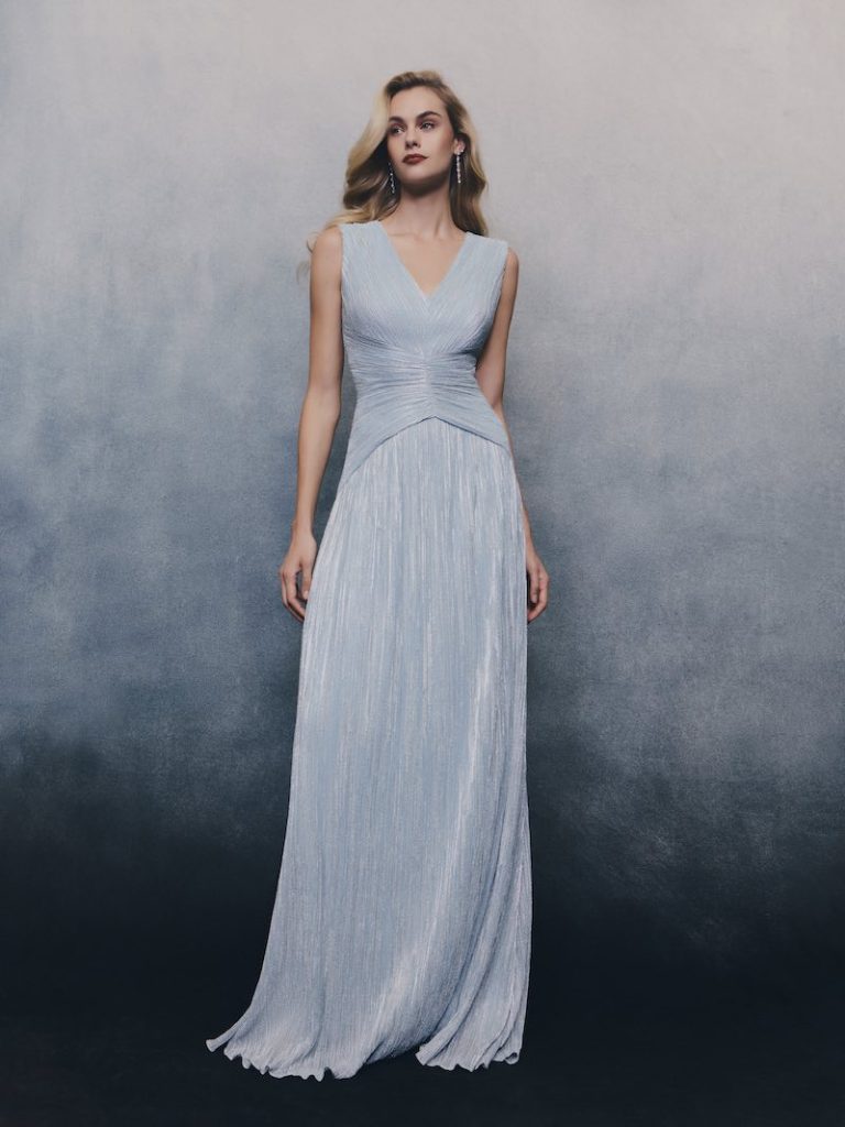 In questa foto una modella posa indossando un abito da cerimonia Pronovias 2026 di colore turchese, modello scivolato con effetto micro plissé 