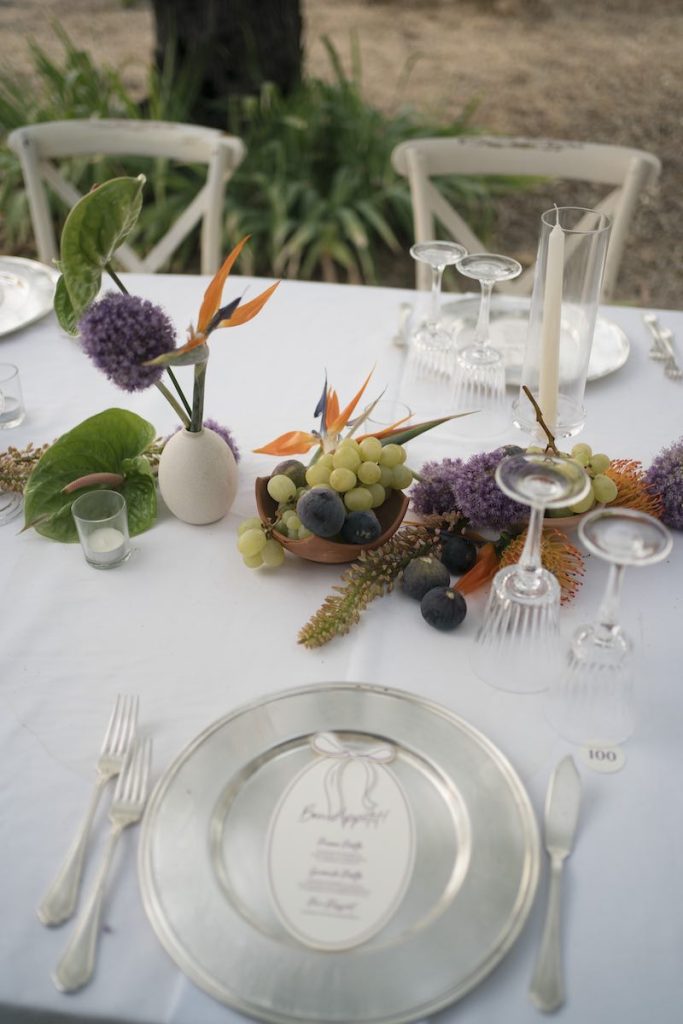 In questa foto il dettaglio di un tavolo imperiale inquadrato in obliquo allestito da Giulia Ferro di Maritari con frutta e fiori di campo