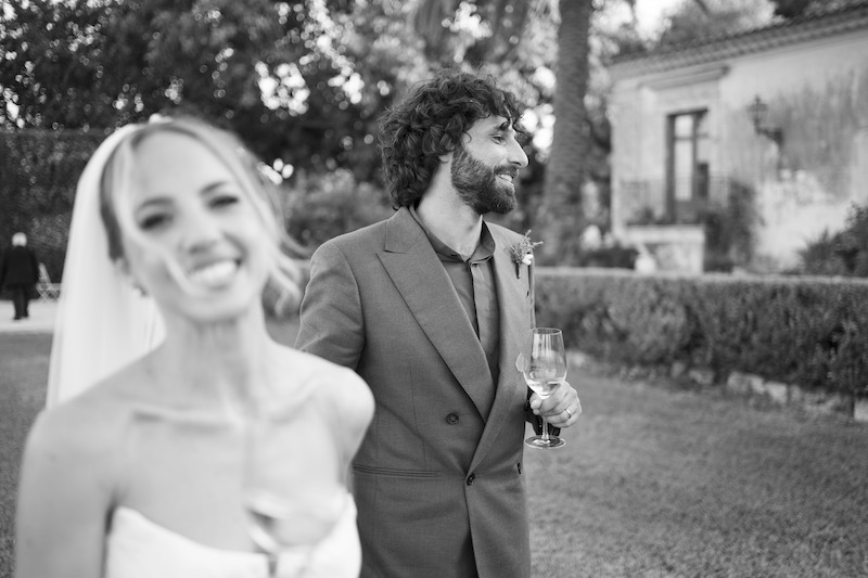 In questa foto in bianco e nero il primo priano di due sposi che camminano in giardino mentre sorridono