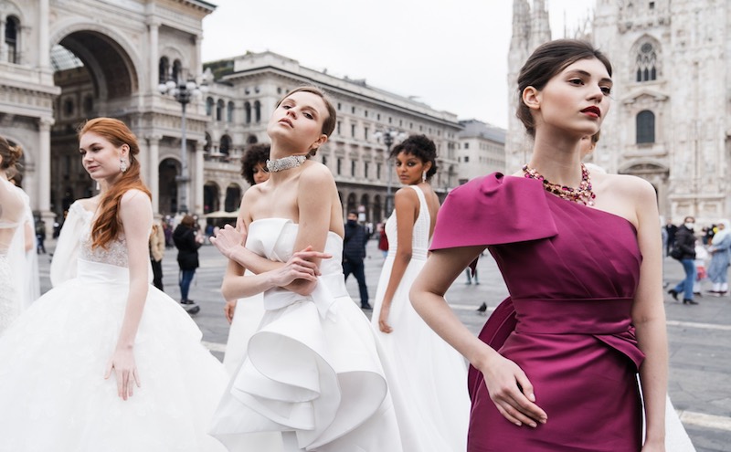 In questa foto modelle in abiti da sposa e cerimonia posano nella piazza di fronte al Duomo di Milano per il Sì Sposaitalia Collezioni 2026