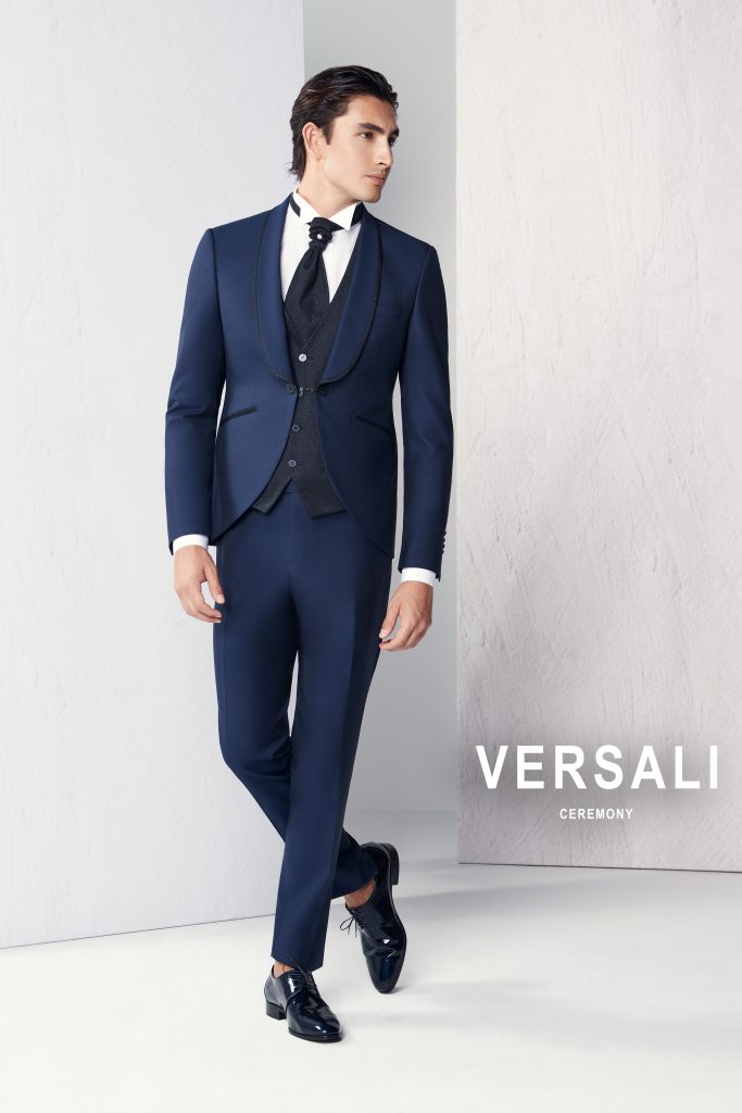 In questa foto, un uomo indossa un abito blu notte con gilet e cravattone nero, mostrando un look formale ma di grande personalità. L'immagine illustra come scegliere abito da sposo per chi vuole distinguersi con stile.