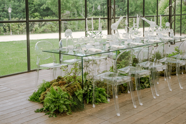 In questa foto, un allestimento contemporaneo colpisce per l’uso di materiali trasparenti: sedie ghost e tavolo in vetro poggiano su una base di muschio e felci, creando un effetto “giungla sotto vetro”. Lo styling minimalista e il design audace fanno di questa composizione una delle tendenze allestimenti matrimonio 2026 più innovative.