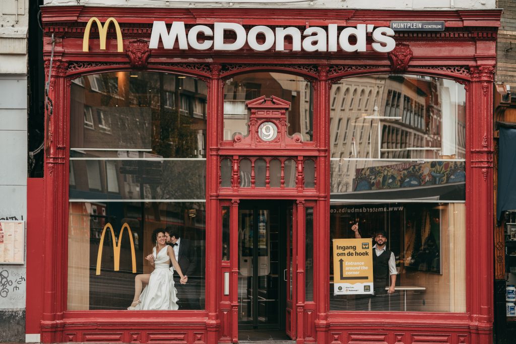 In questa foto si vede una delle caratteristiche dei matrimoni Gen Z, raccontata da una posa ironica e urbana degli sposi dentro uno store Mc Donalds simbolo di uno stile anticonvenzionale e contemporaneo.