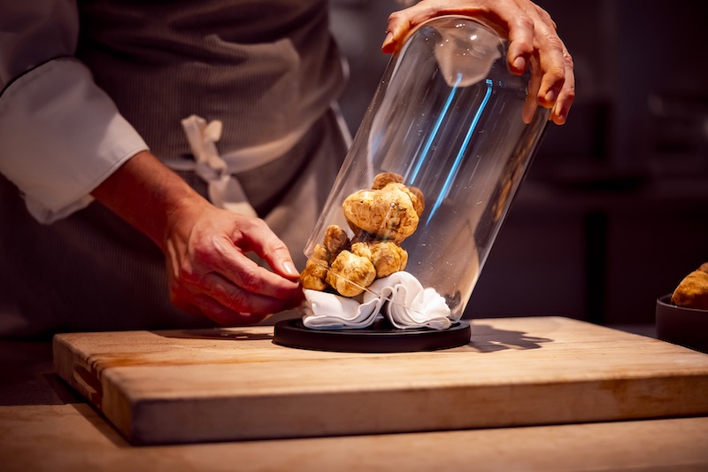 In questa foto, il dettaglio di uno chef che fa fuoriuscire alcuni tartufi bianchi d'Alba da una teca di vetro