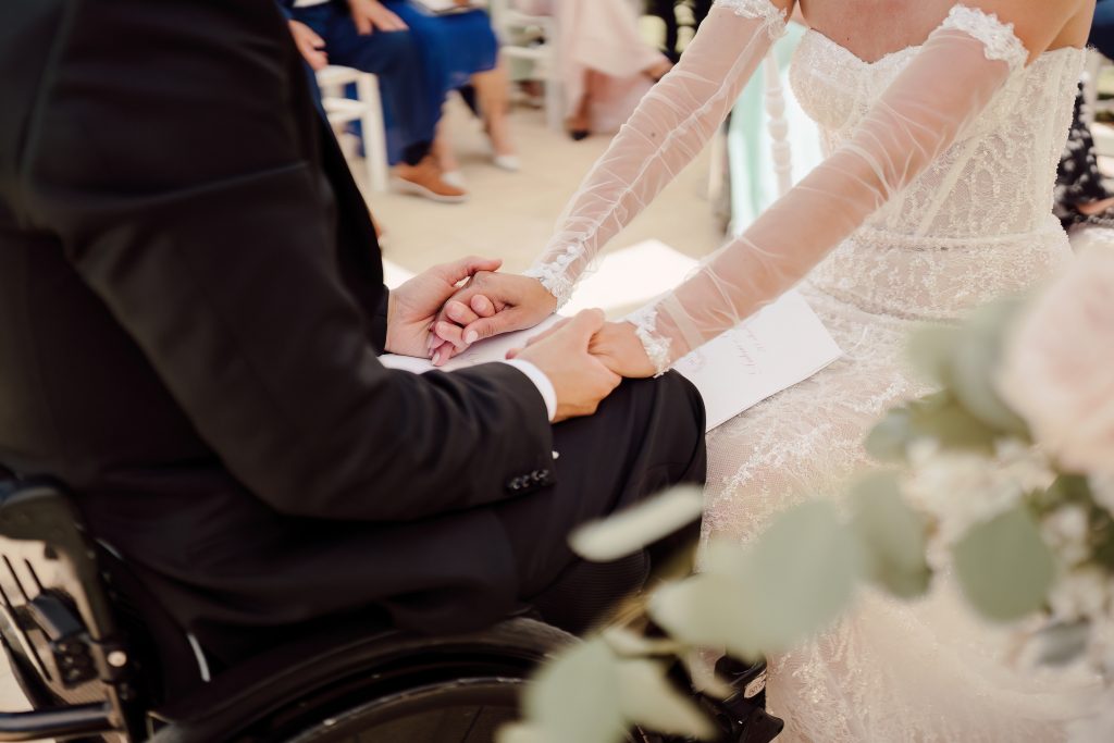 In questa foto si vede una delle caratteristiche dei matrimoni Gen Z, attraverso un dettaglio ravvicinato delle mani degli sposi che si stringono durante la cerimonia, mettendo al centro l’emozione, l’inclusività e il legame autentico.