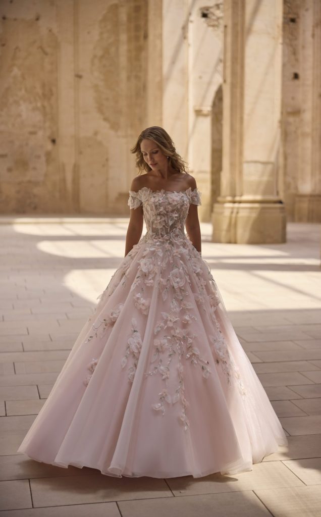 In questa foto si vede una delle caratteristiche dei matrimoni Gen Z, rappresentata da una sposa che indossa un abito romantico e colorato, fotografata in un contesto architettonico storico che valorizza luce naturale ed eleganza senza eccessi.