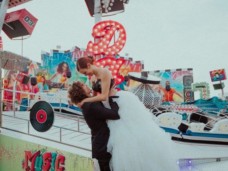 In questa foto di vede una delle caratteristiche dei matrimoni Gen Z, rappresentata da una scena giocosa e fuori dagli schemi in cui gli sposi interagiscono in un luna park, rompendo le regole della fotografia matrimoniale tradizionale.