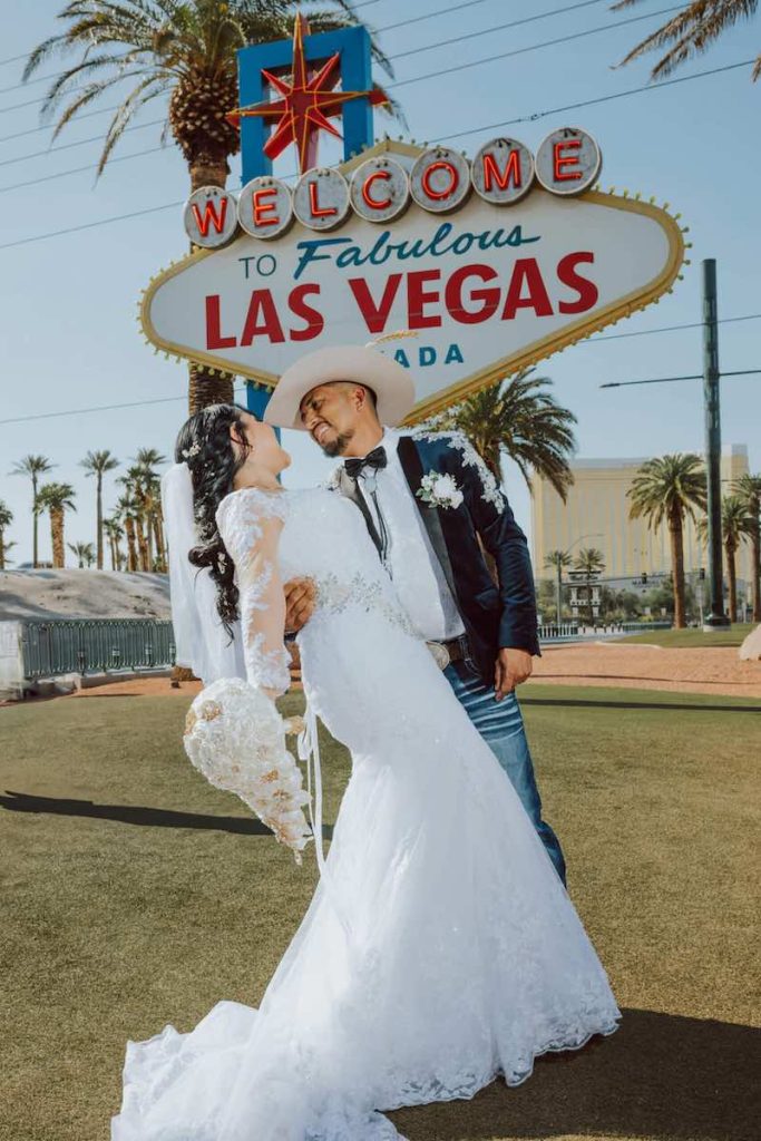 In questa foto, due sposi si guardano felici dopo il loro matrimonio mentre si trovano davanti all'insegna "Welcome to fabulous Las Vegas Nevada"