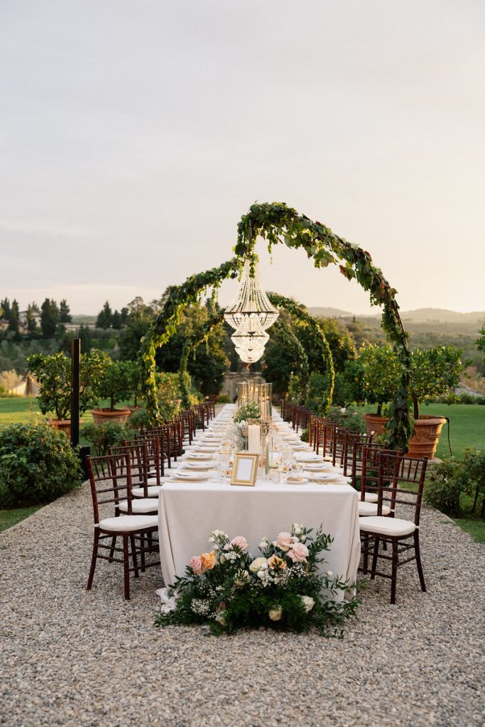 In questa foto di vede una delle caratteristiche dei matrimoni della nuova generazione, attraverso una tavola imperiale immersa nel paesaggio, decorata con verde naturale, fiori delicati e un grande lampadario scenografico.