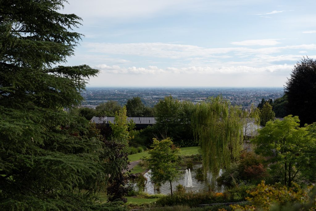 In questa foto si vede uno degli ambienti dedicati al ricevimento matrimonio al Phi Hotel Piajo: il panorama collinare che circonda la struttura. Il giardino curato si affaccia su una vallata, con fontane, alberi rigogliosi e una vista ampia che arriva fino alla città.