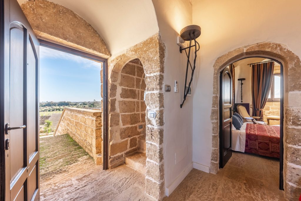 In questa foto si vede uno degli spazi di un matrimonio a a Tenuta Monacelli, un corridoio interno in pietra con archi e porte che si aprono su una terrazza panoramica affacciata sulla campagna.
