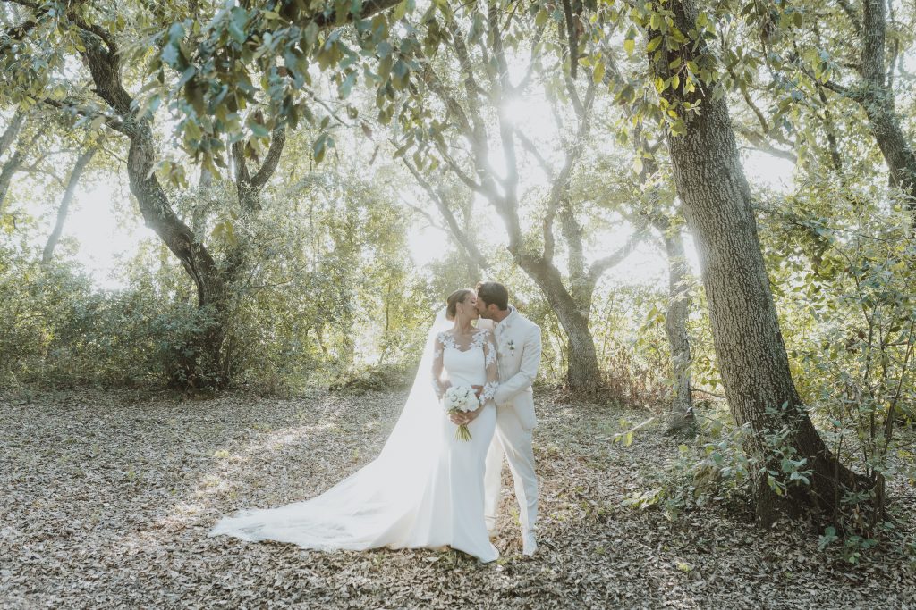 In questa foto si vede uno degli spazi di un matrimonio a a Tenuta Monacelli, gli sposi che si baciano in un boschetto di ulivi, circondati da luce naturale filtrata tra le foglie.