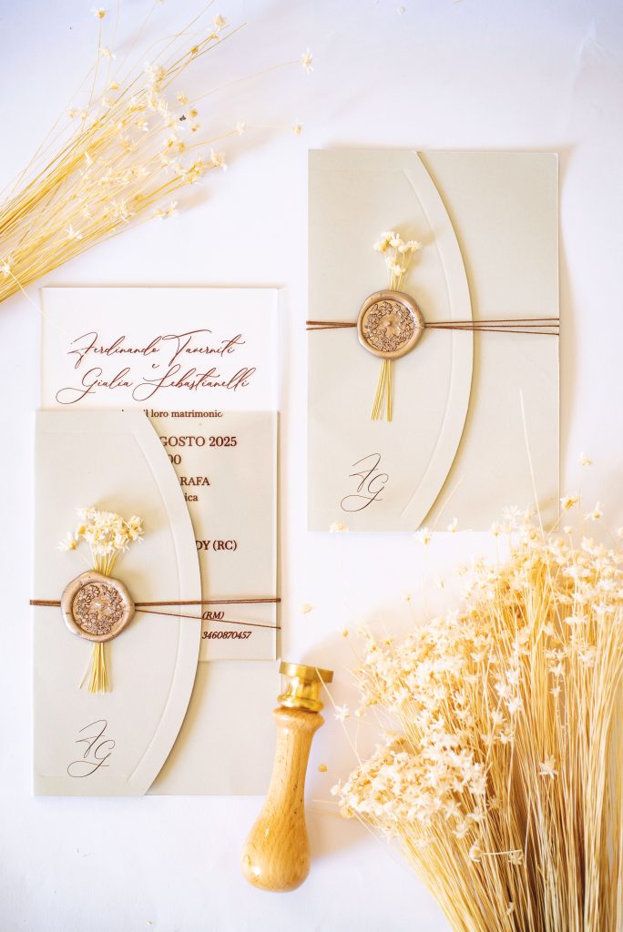 In questa foto si vede una delle tendenze partecipazioni matrimonio 2026: la carta materica color burro, avvolta da spago naturale e fiori secchi, chiusa con sigillo in ceralacca. Lo stile è semplice ma sofisticato, perfetto per matrimoni ispirati alla natura e al minimalismo elegante.