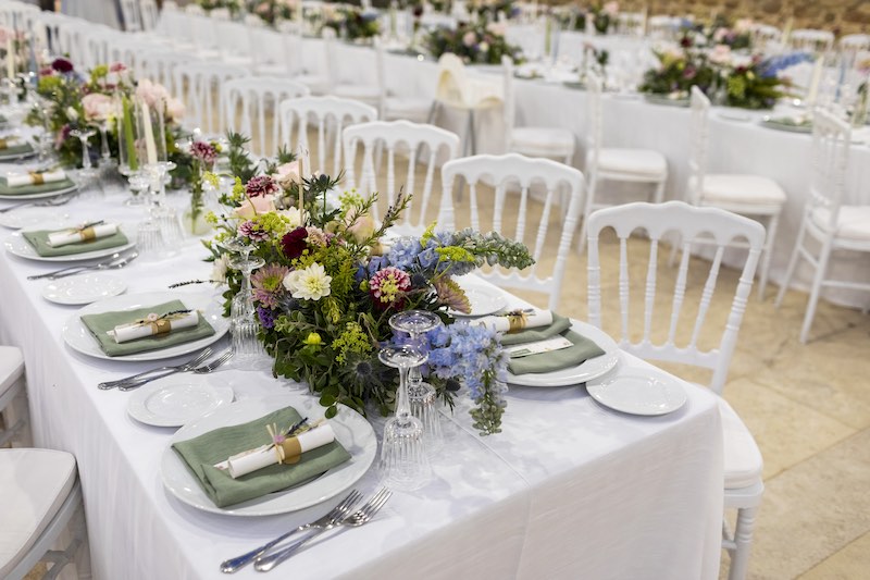 In questa foto, l'allestimento di un ricevimento di nozze con tavoli imperiali e composizioni di fiori nei toni del lilla, del rosa e del verde
