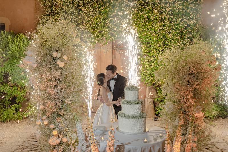 In questa foto, due sposi che si baciano al taglio della torta in un allestimento di gypsophila bianca
