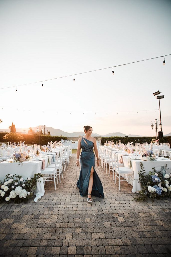 In questa foto Barbara Trentacosti, direttrice artistica di Barbara Eventi durante l’allestimento di un matrimonio con direzione artistica tra tavoli decorati al tramonto.