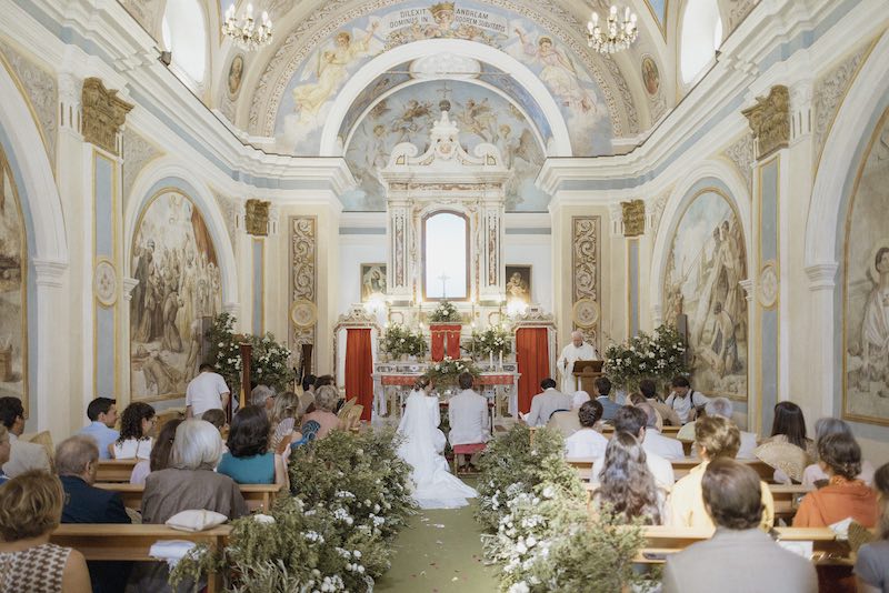 In questa foto, una foto panoramica della chiesa del matrimonio di Camilla e Niccolò allestita da Elena Bitonte con fiori di colore bianco e ulivi