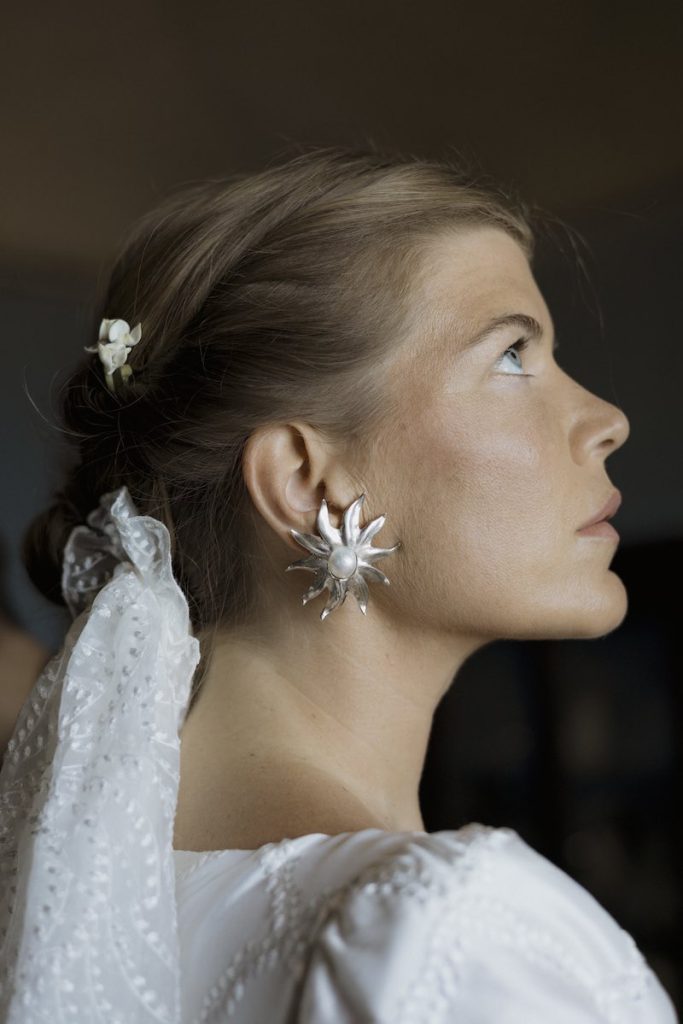 In questa foto, il dettaglio dell'orecchino a forma di fiore indossato dalla sposa
