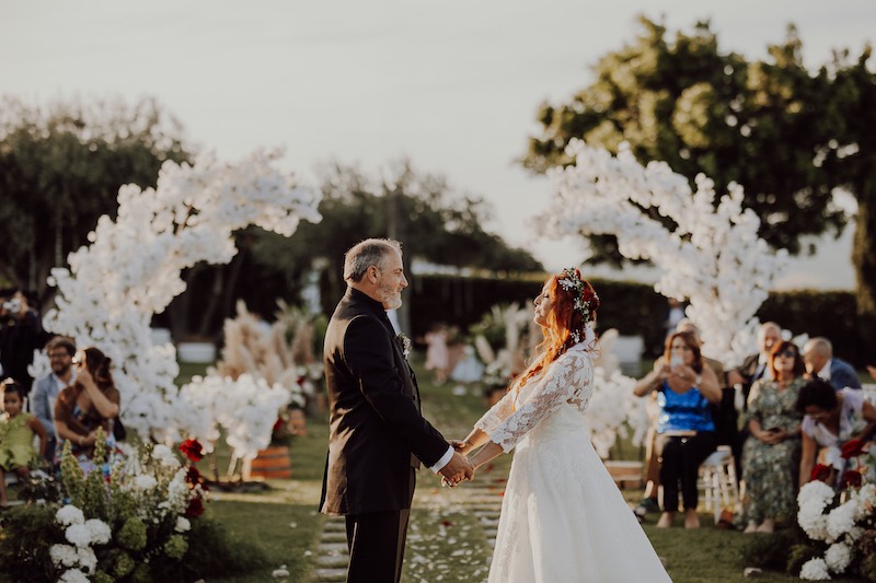 In questa foto due sposi durante lo scambio delle promesse, tra allestimenti floreali curati dalla direzione artistica di Barbara Eventi.