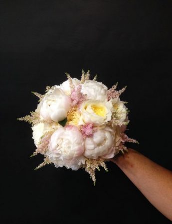 In questa foto un bouquet da sposa di peonie bianche e fiori di campo rosa