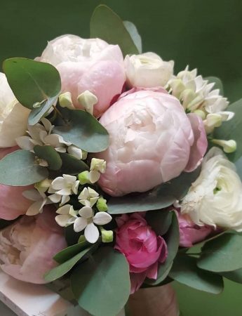 In questa foto un bouquet da sposa con peonie rosa e fiori bianchi