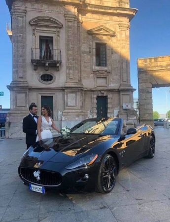 In questa foto una coppia di sposi posa con l'auto presa a noleggio da Elegance Car Liguori