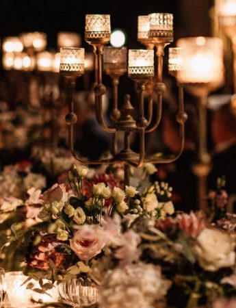 In questa foto una mise en place per un matrimonio romantico. Il tavolo è decorato con candelabri dorati e vasi di fiori rosa e bianchi