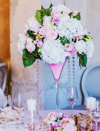 In questa foto una mise en place per un matrimonio romantico nei colori del rosa e del bianco. Un grande vaso a cono con fiori rosa e bianchi è usato come centrotavola