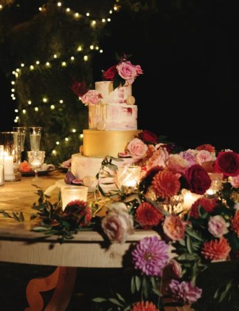 In questa foto l'allestimento del tavolo di una torta nuziale in stile luxury nei toni del rosa, del bordeaux e dell'oro