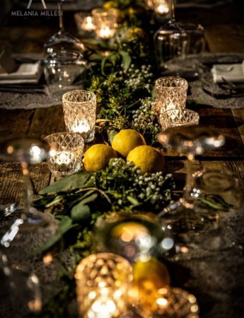 In questa foto la mise en place di un tavolo imperiale con bicchieri e candele di cristallo decorato. Limoni e foglie sono usati come runner e per ogni ospite viene usata una tovaglietta in pizzo