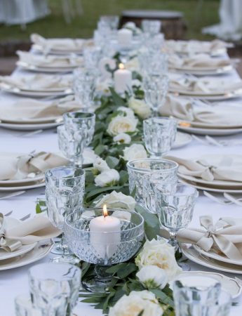 In questa foto un tavolo imperiale con runner di foglie e rose bianche